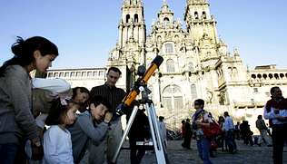 Niños observando por turno por un refractor delante de la catedral de Santiago de Compostela.